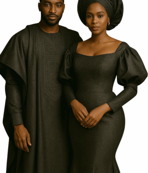 An elegant African couple wearing matching agbada outfits made from rich brocade fabric, standing side by side in a luxurious indoor setting.