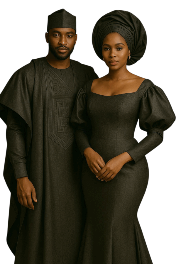 An elegant African couple wearing matching agbada outfits made from rich brocade fabric, standing side by side in a luxurious indoor setting.