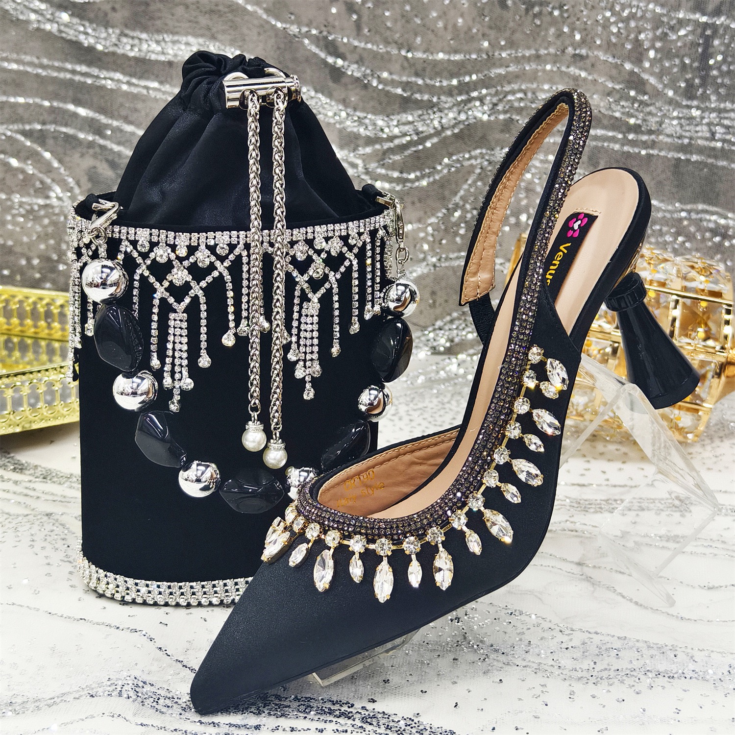 A pair of black satin slingback heels embellished with teardrop crystals, paired with a matching black velvet bag featuring crystal fringe and bold beads.