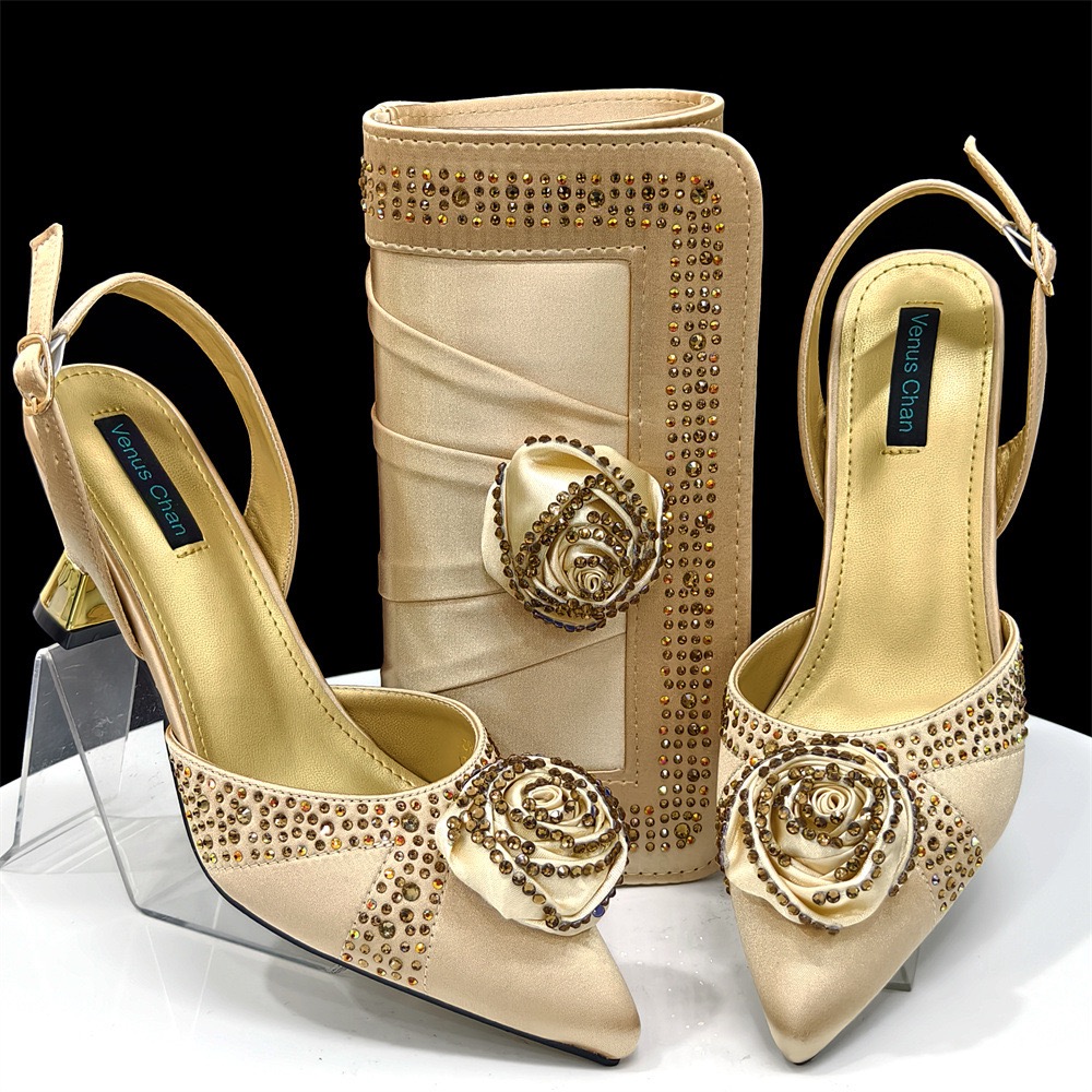 A gold satin women’s heel and clutch set decorated with rhinestones and floral appliques, displayed on a white surface.